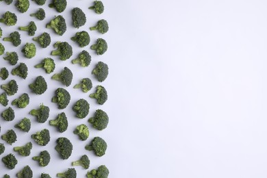 Many fresh green broccoli pieces on white background, flat lay. Space for text