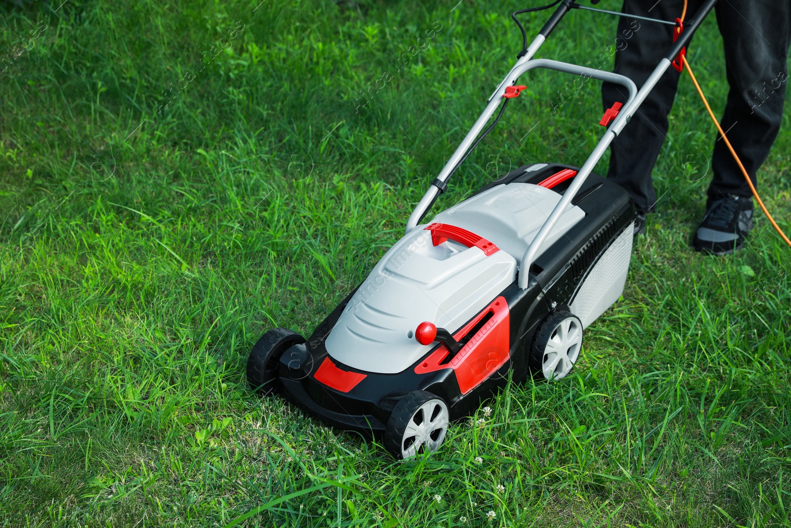 Photo of Man cutting grass with lawn mower in garden, closeup. Space for text