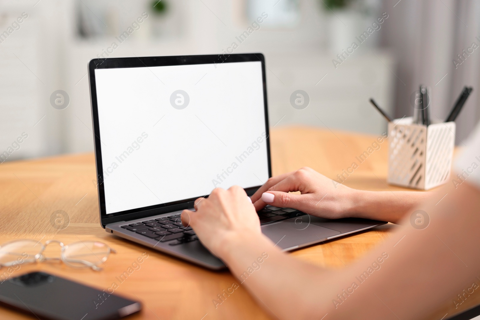 Photo of Young woman watching webinar at table indoors, closeup