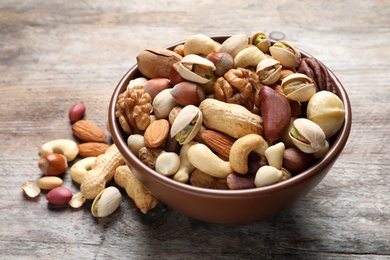 Photo of Bowl with mixed organic nuts on wooden background