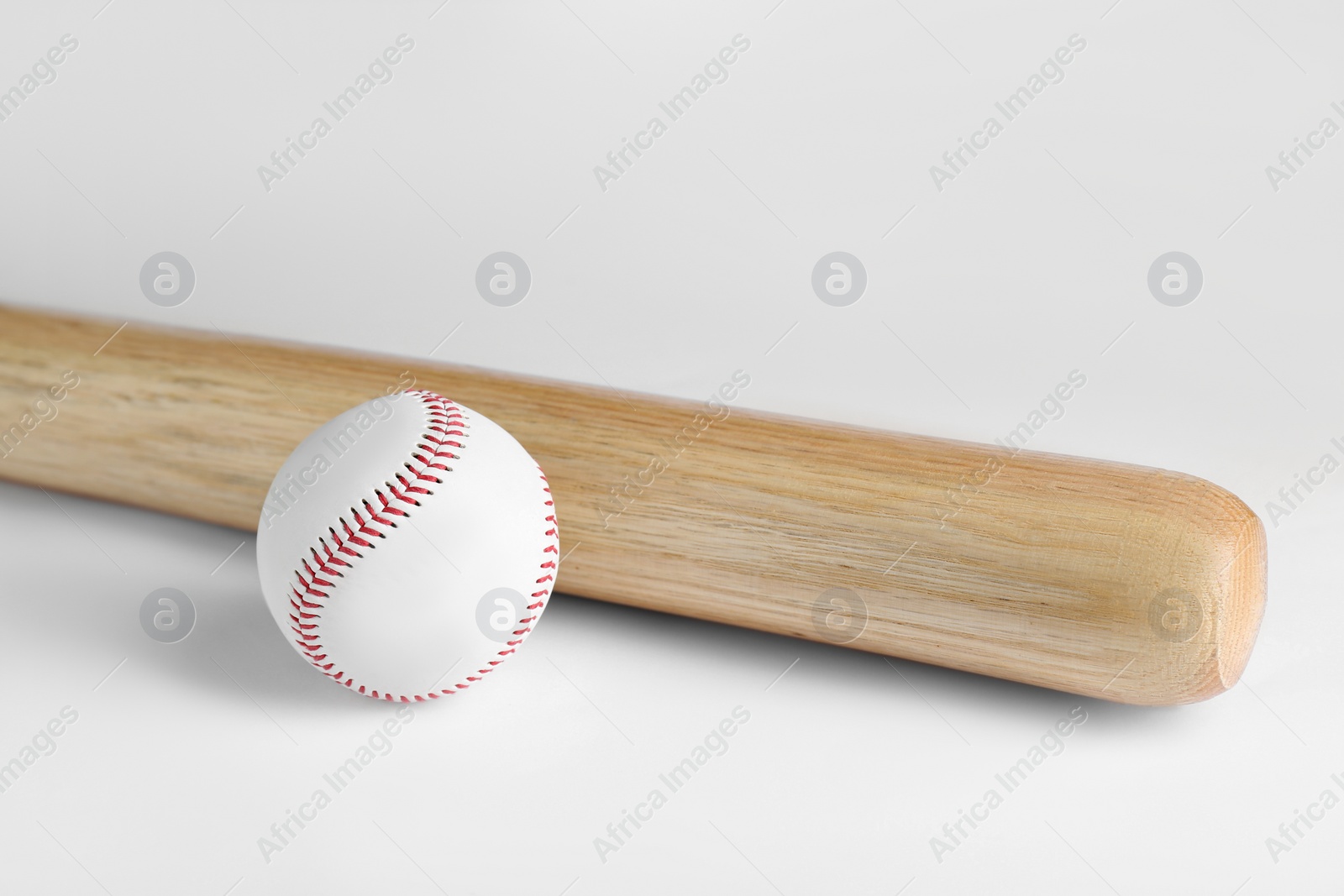 Photo of Wooden baseball bat and ball on white background. Sports equipment