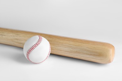 Photo of Wooden baseball bat and ball on white background. Sports equipment