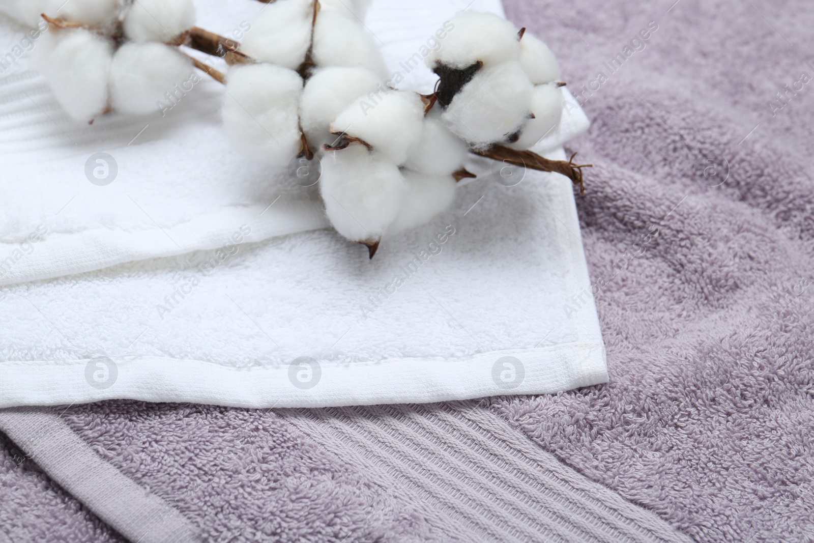 Photo of Cotton flowers on different terry towels, closeup