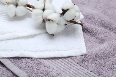 Photo of Cotton flowers on different terry towels, closeup