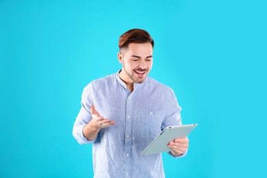 Photo of Man using tablet for video chat on color background