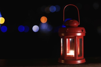 Photo of Lantern on wooden railing outdoors against blurred background, space for text. Winter night