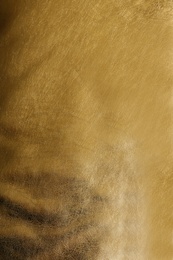 Photo of Shiny golden leather as background, top view