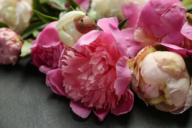 Photo of Beautiful fragrant peonies on black slate table, closeup