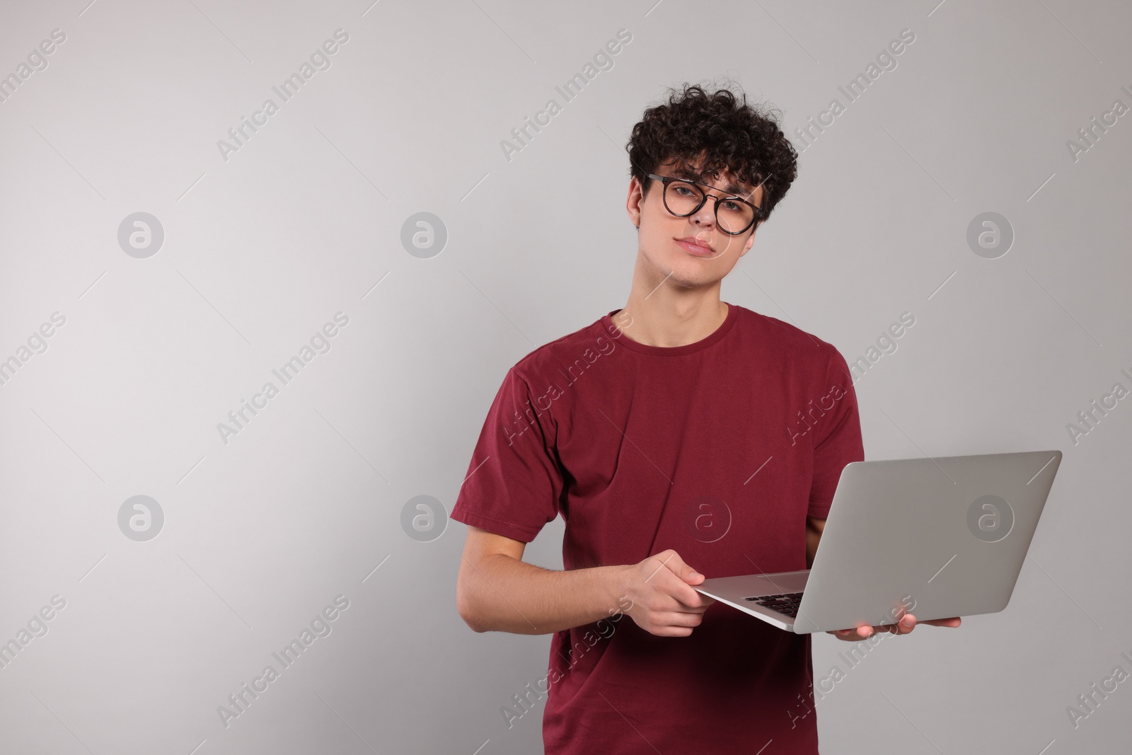 Photo of Handsome young man using laptop on light grey background. Space for text