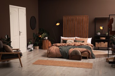 Photo of Stylish room interior with large bed near brown wall