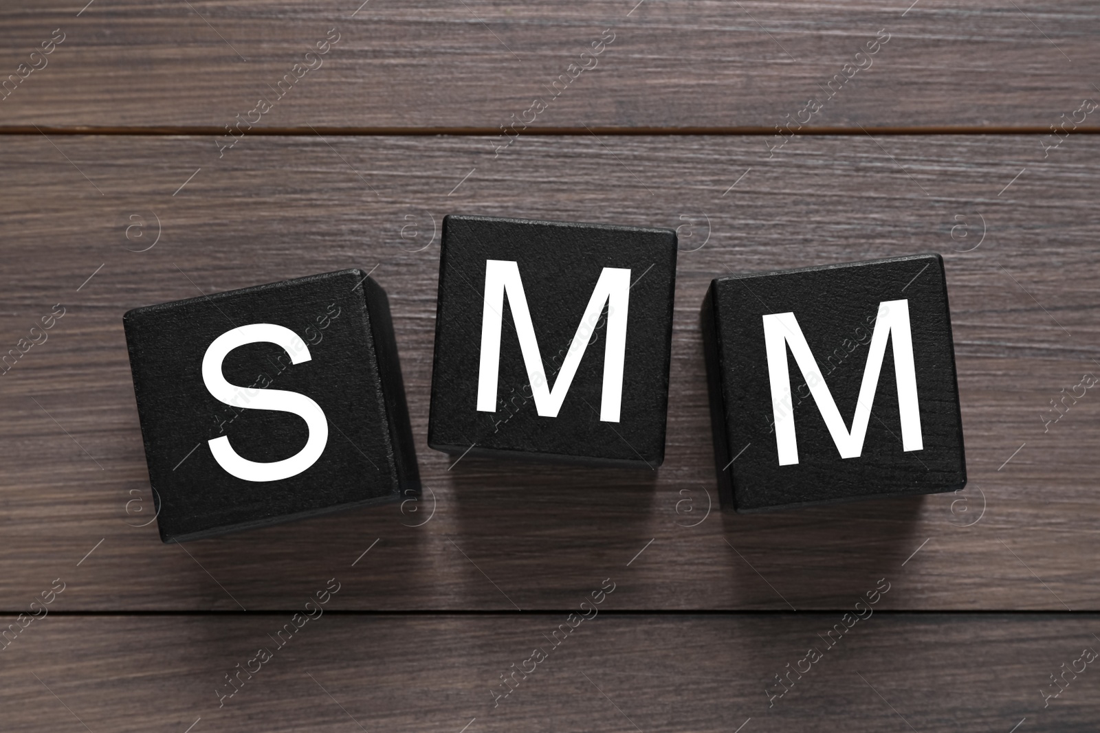 Photo of Black cubes with abbreviation SMM (Social media marketing) on wooden table, flat lay