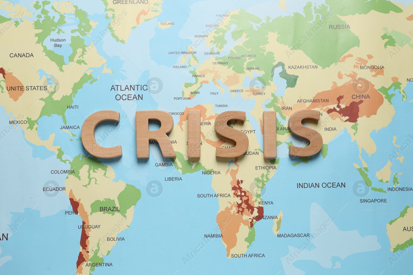 Photo of Word Crisis made of wooden letters on world map, flat lay