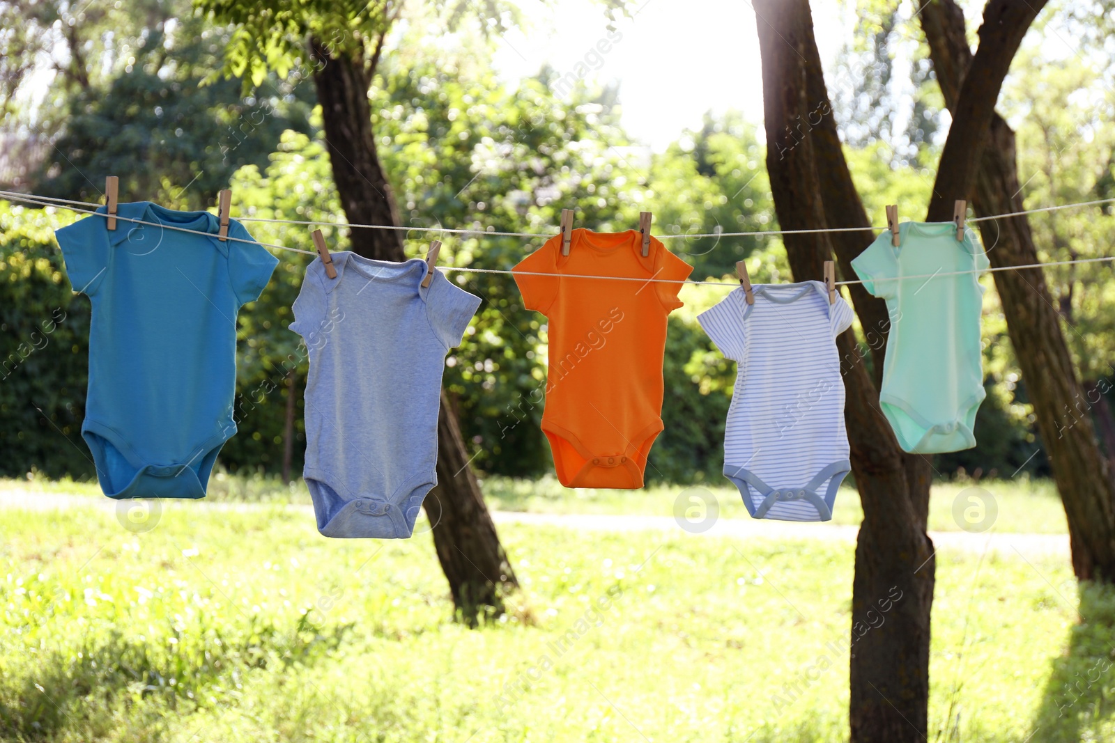 Photo of Colorful baby onesies hanging on clothes line outside