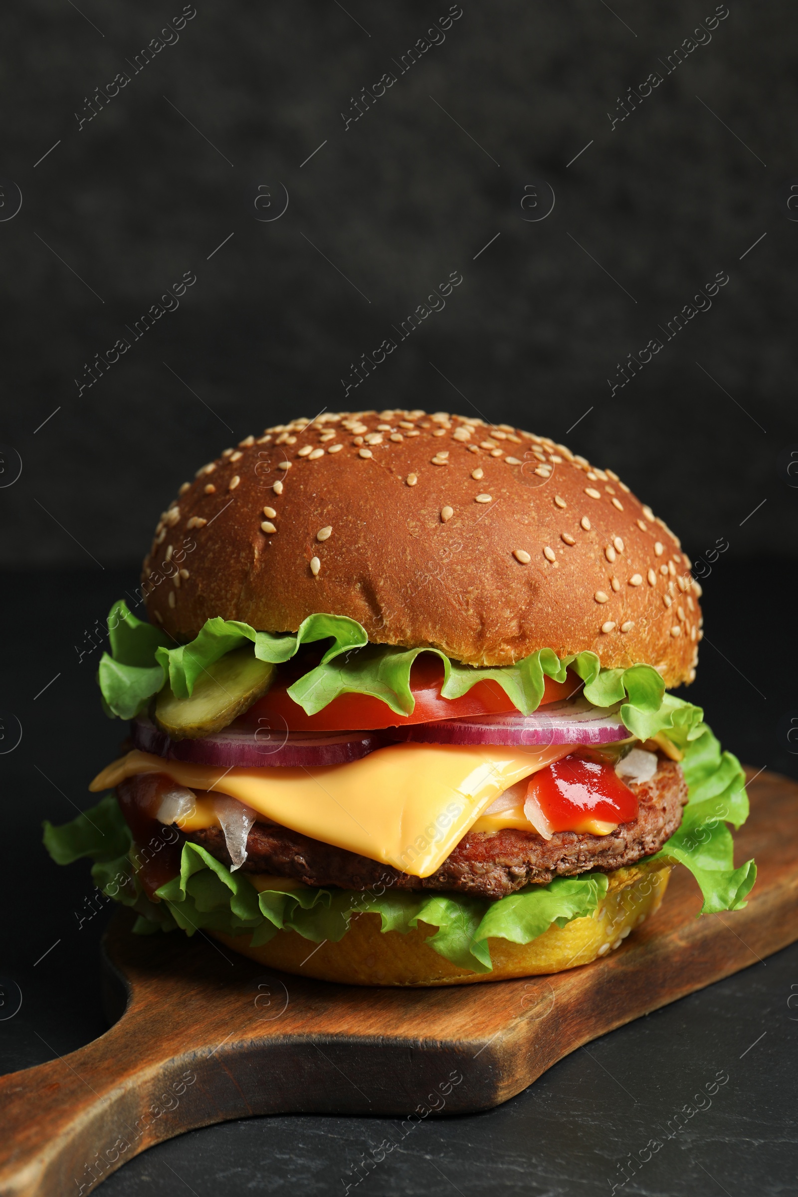 Photo of Delicious burger with beef patty and lettuce on dark table