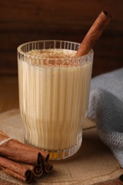 Photo of Glass of delicious eggnog with cinnamon on wooden table