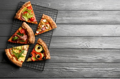 Slices of different delicious pizzas on grey wooden table, flat lay. Space for text
