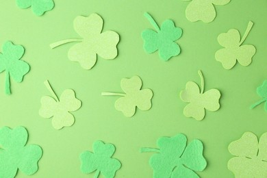 St. Patrick's day. Decorative clover leaves on green background, flat lay