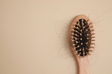 Wooden brush with lost hair on beige background, top view. Space for text