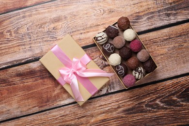 Photo of Open box with delicious chocolate candies on wooden table, top view