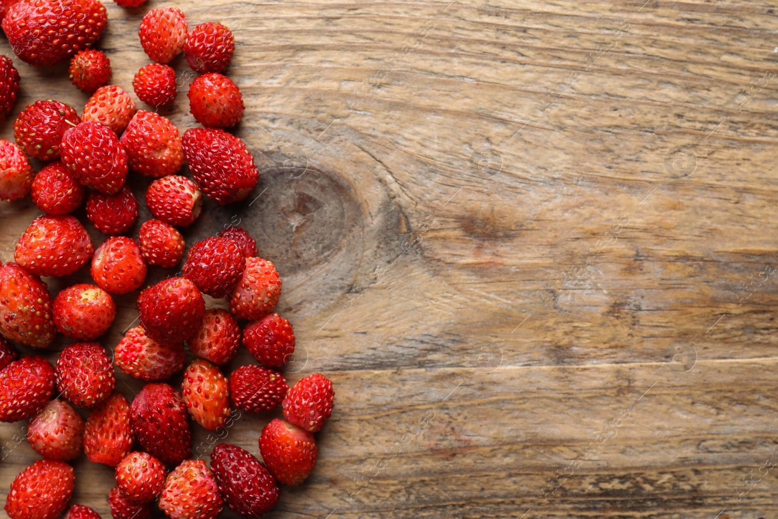 Photo of Many fresh wild strawberries on wooden table, flat lay. Space for text