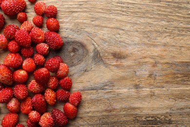 Many fresh wild strawberries on wooden table, flat lay. Space for text