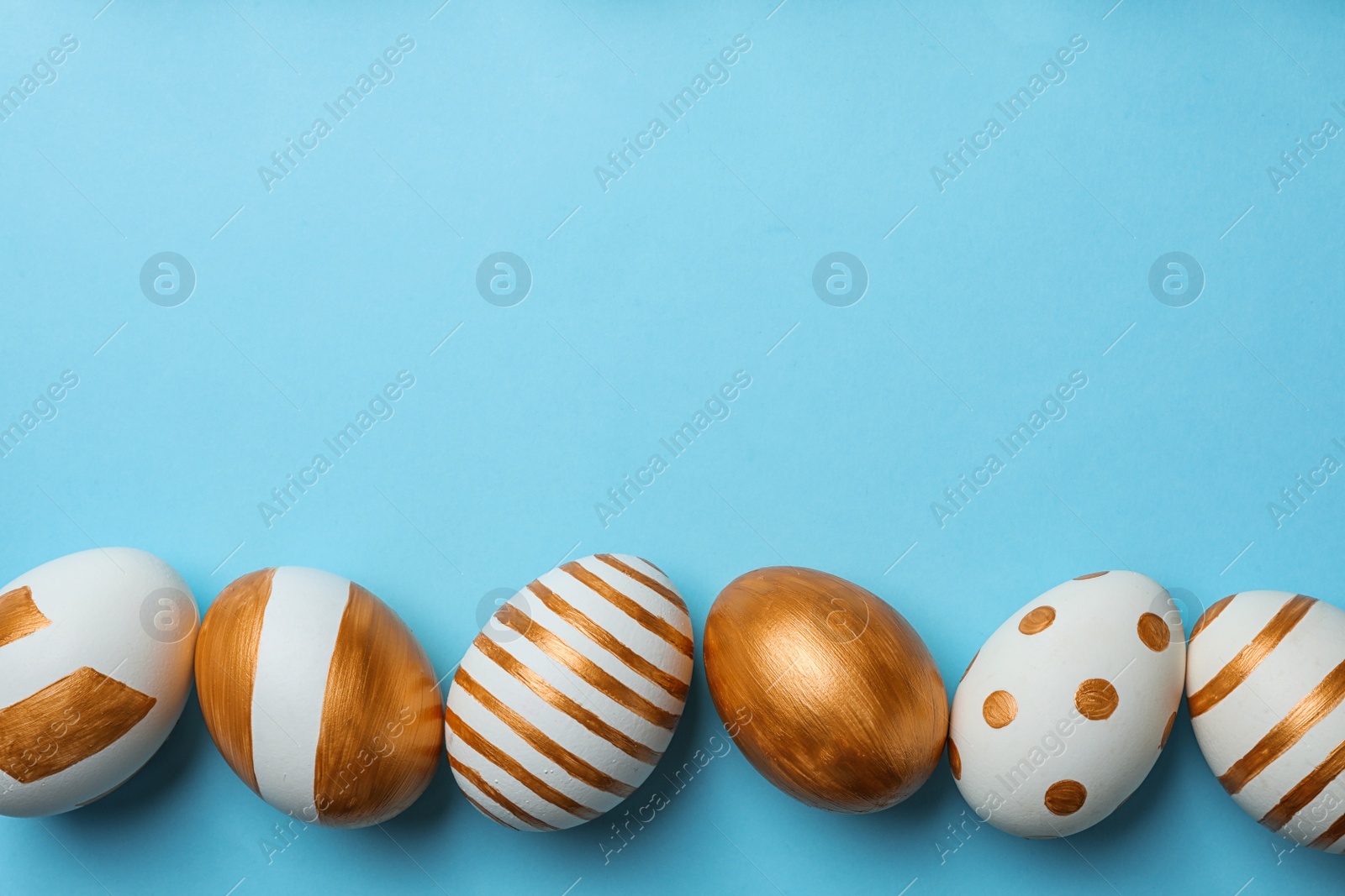 Photo of Set of traditional Easter eggs decorated with golden paint on color background, top view. Space for text