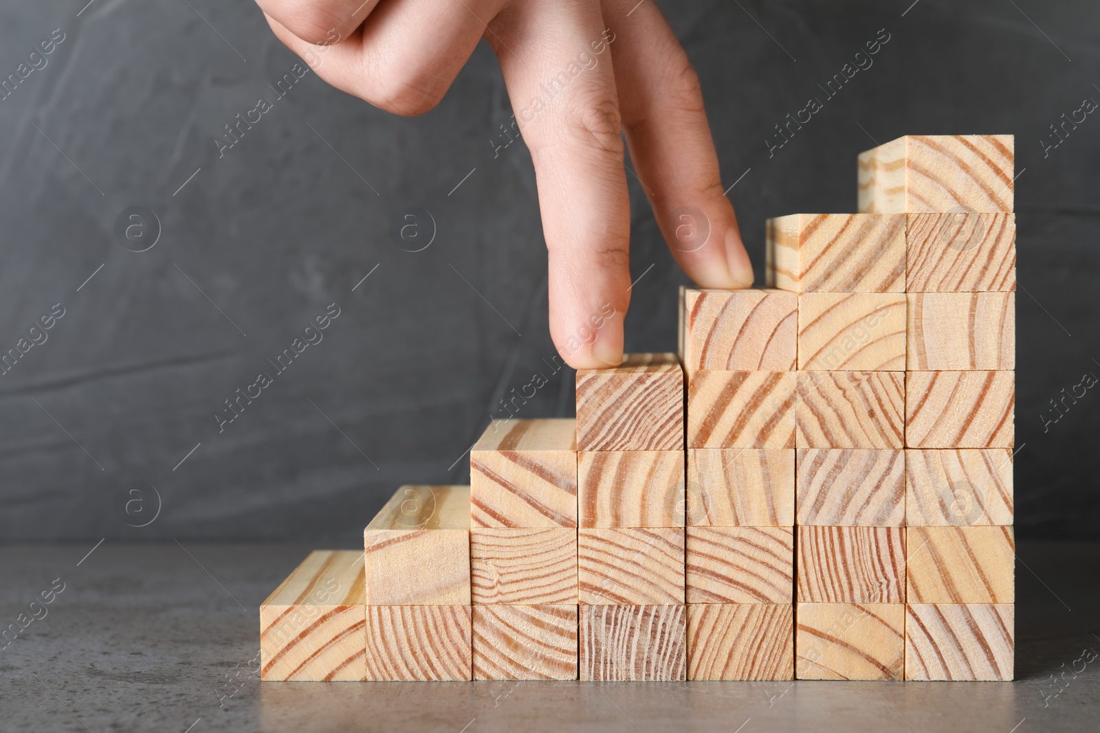 Photo of Man imitating stepping up on wooden stairs with his fingers, closeup. Career ladder