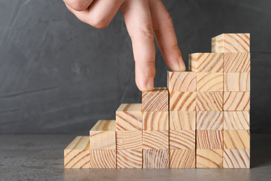 Photo of Man imitating stepping up on wooden stairs with his fingers, closeup. Career ladder