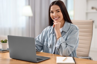 Young woman watching webinar at table in room