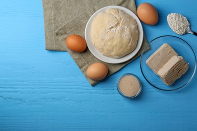 Photo of Different types of yeast, eggs, dough and flour on light blue wooden table, flat lay. Space for text