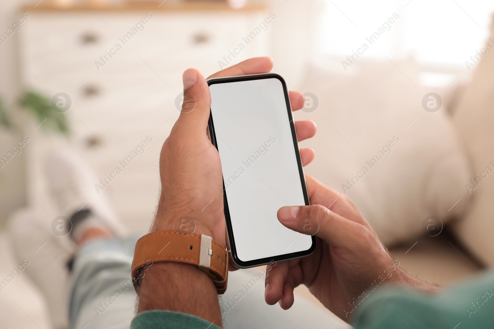 Photo of Man using mobile phone with empty screen indoors, closeup