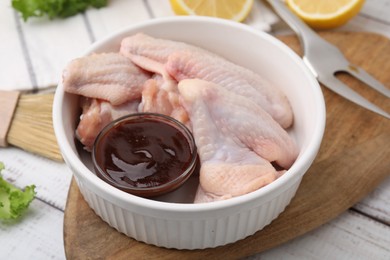 Fresh marinade and raw chicken wings on rustic wooden table, closeup