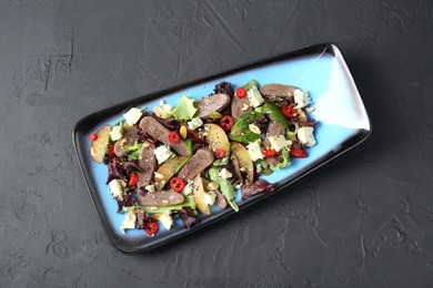 Photo of Delicious salad with beef tongue and cheese on black textured table, top view