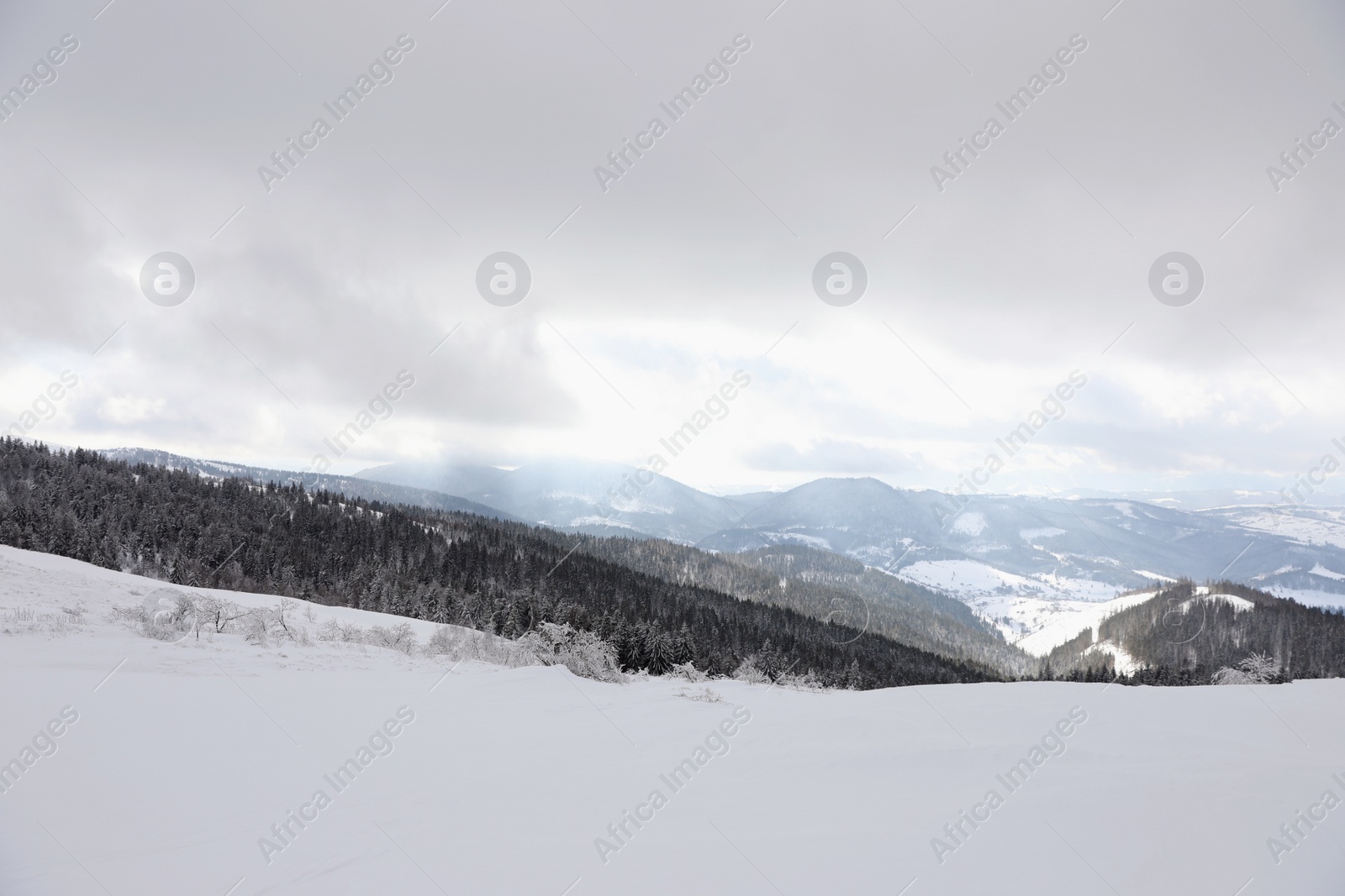 Photo of Picturesque mountain landscape with snowy hills under cloudy sky