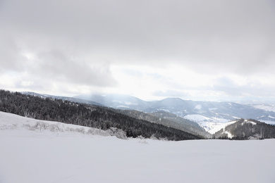 Photo of Picturesque mountain landscape with snowy hills under cloudy sky