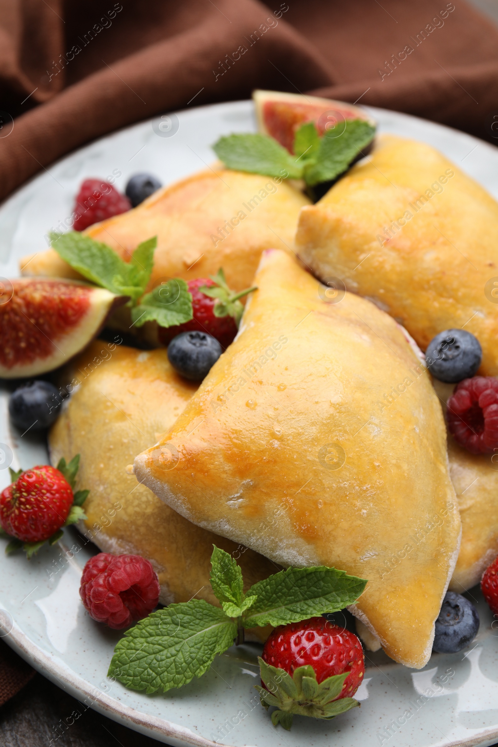 Photo of Delicious samosas with figs and berries on table, closeup