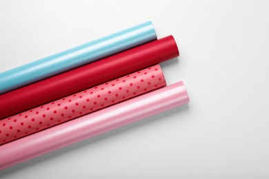 Photo of Rolls of colorful wrapping papers on white background, top view