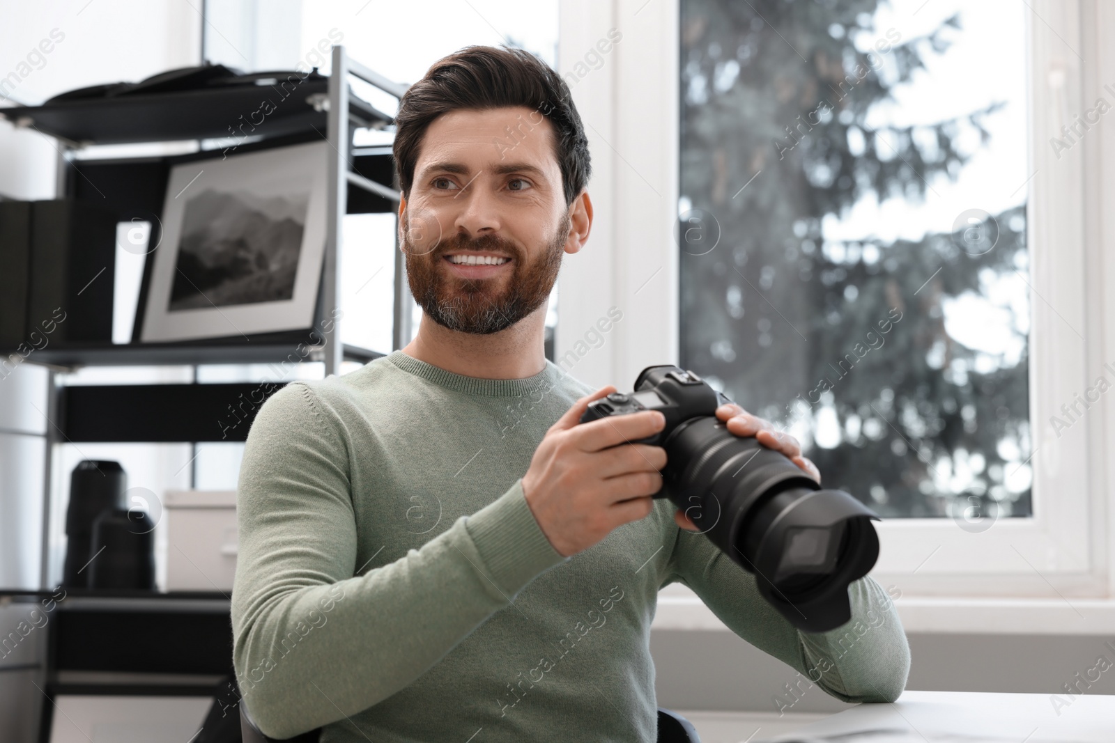 Photo of Professional photographer with digital camera at table in office