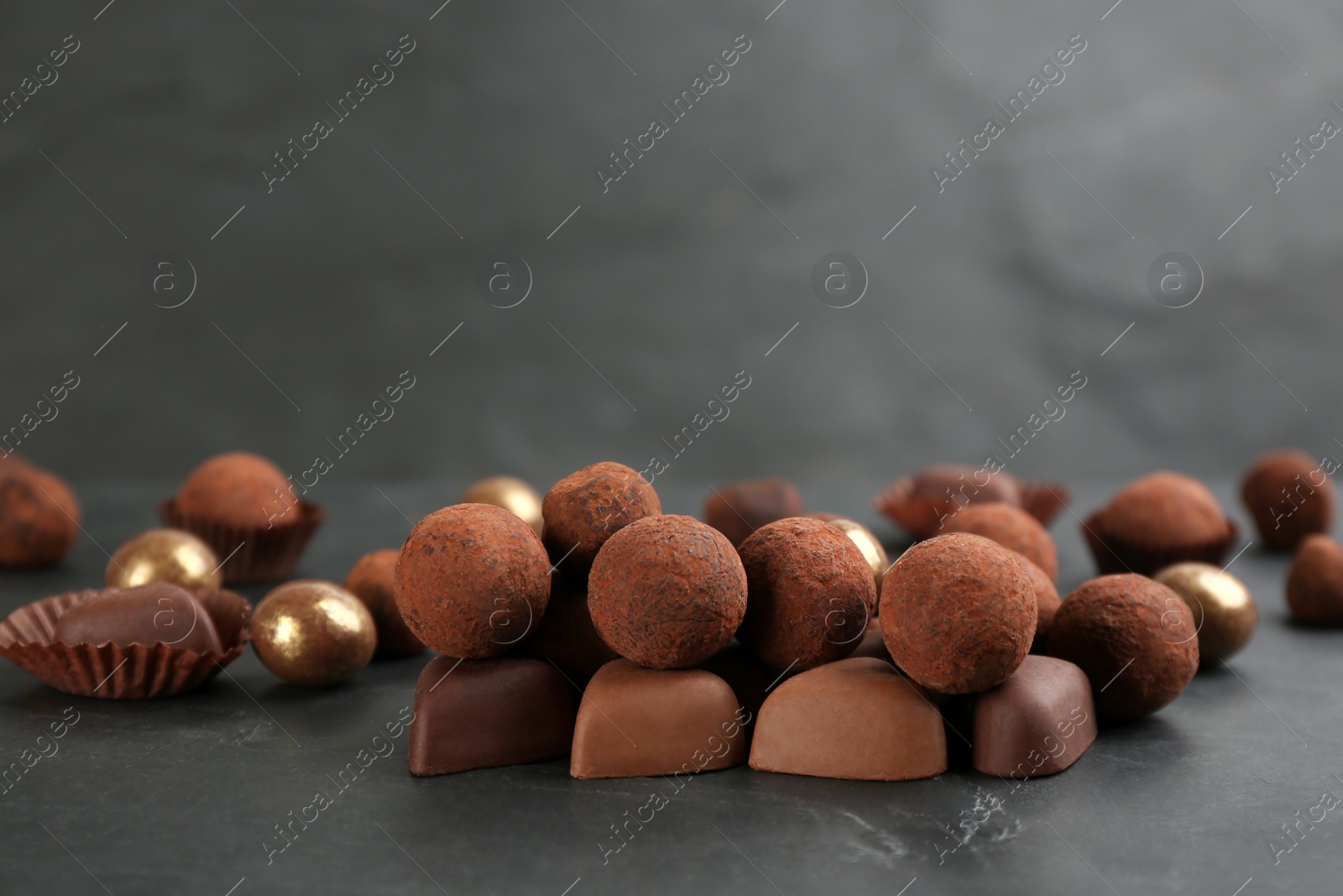 Photo of Different delicious chocolate candies on black table