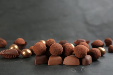 Photo of Different delicious chocolate candies on black table