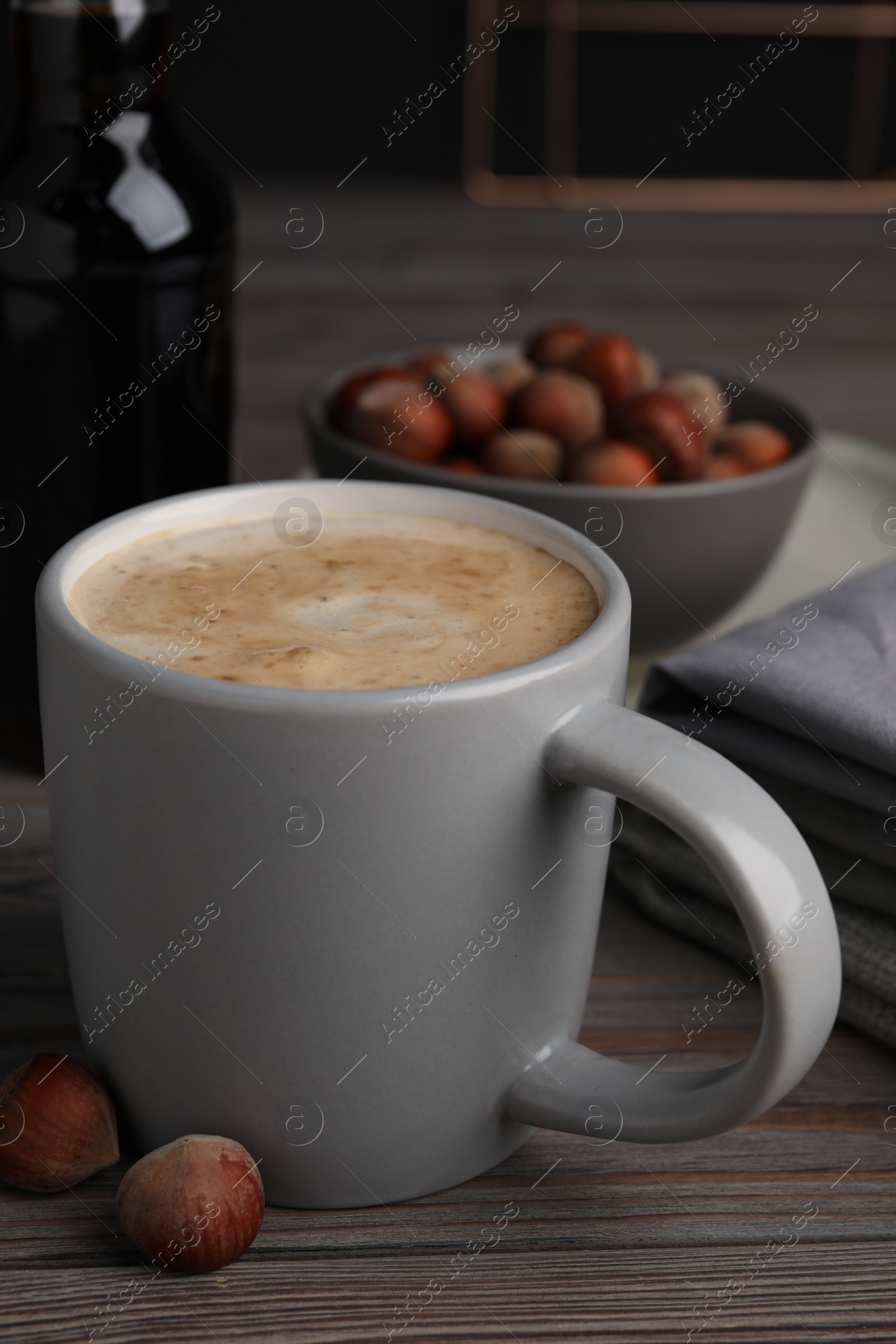 Photo of Mug of delicious coffee with hazelnut syrup on wooden table, closeup