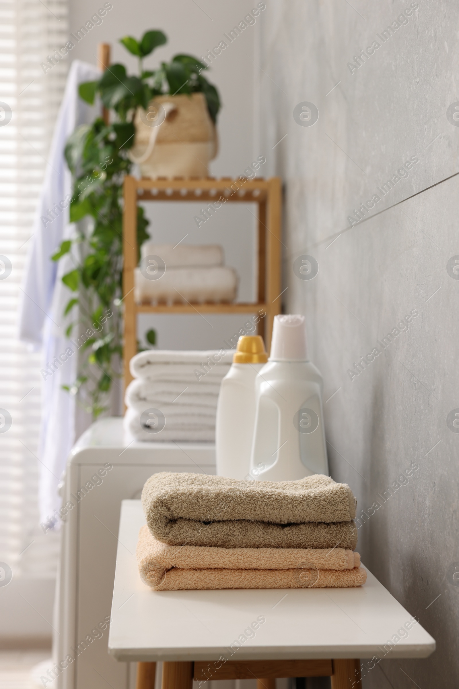 Photo of Soft towels, detergents and shelving unit indoors