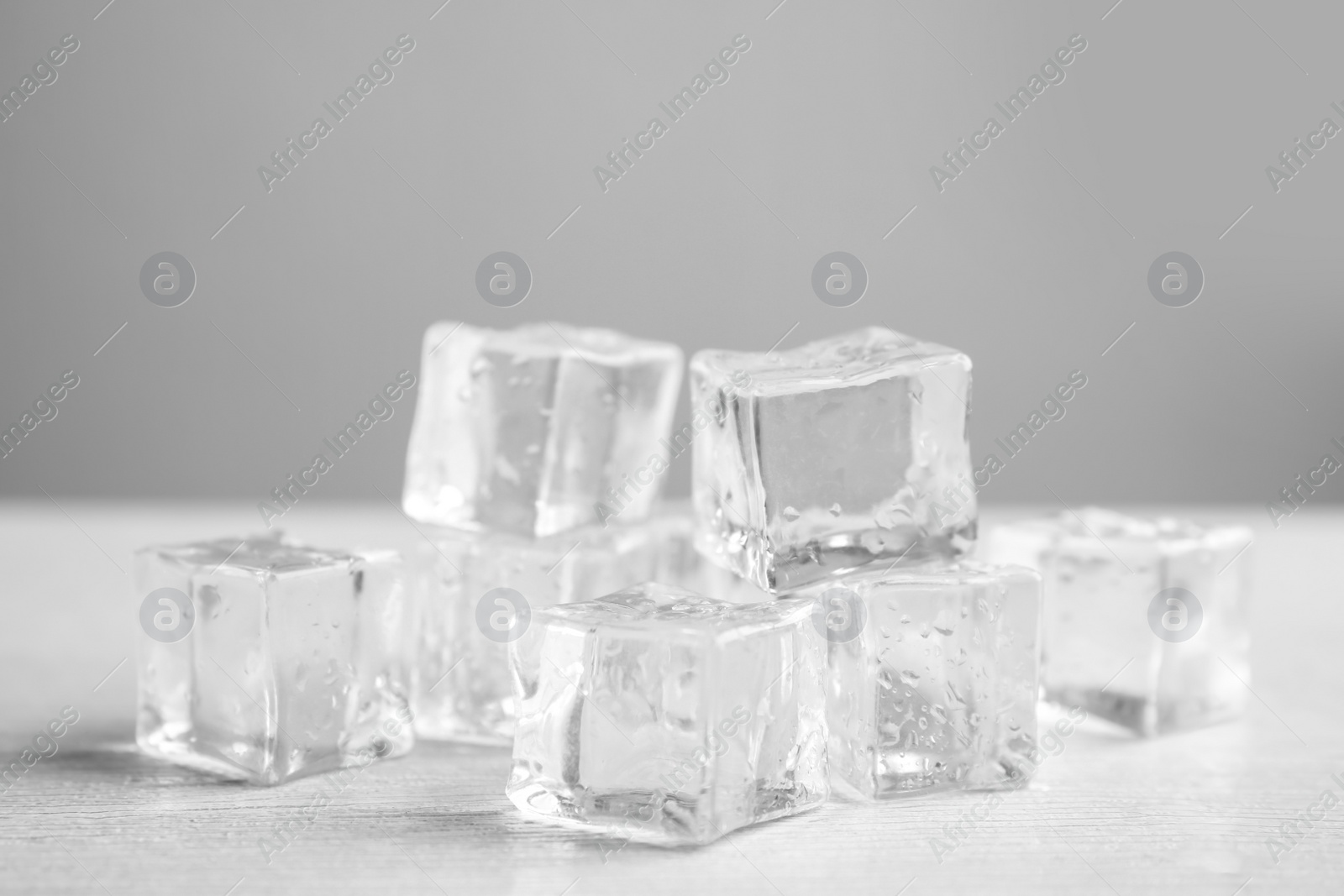 Photo of Ice cubes with water drops on white wooden table, closeup