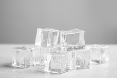 Photo of Ice cubes with water drops on white wooden table, closeup