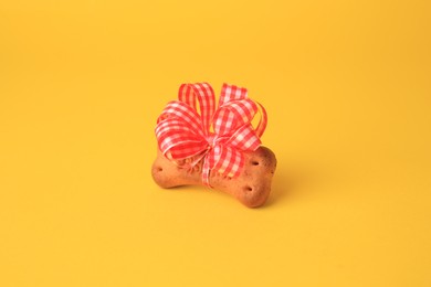 Bone shaped dog cookie with bow on yellow background