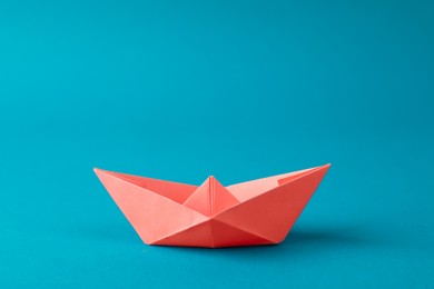 Photo of Handmade pink paper boat on light blue background
