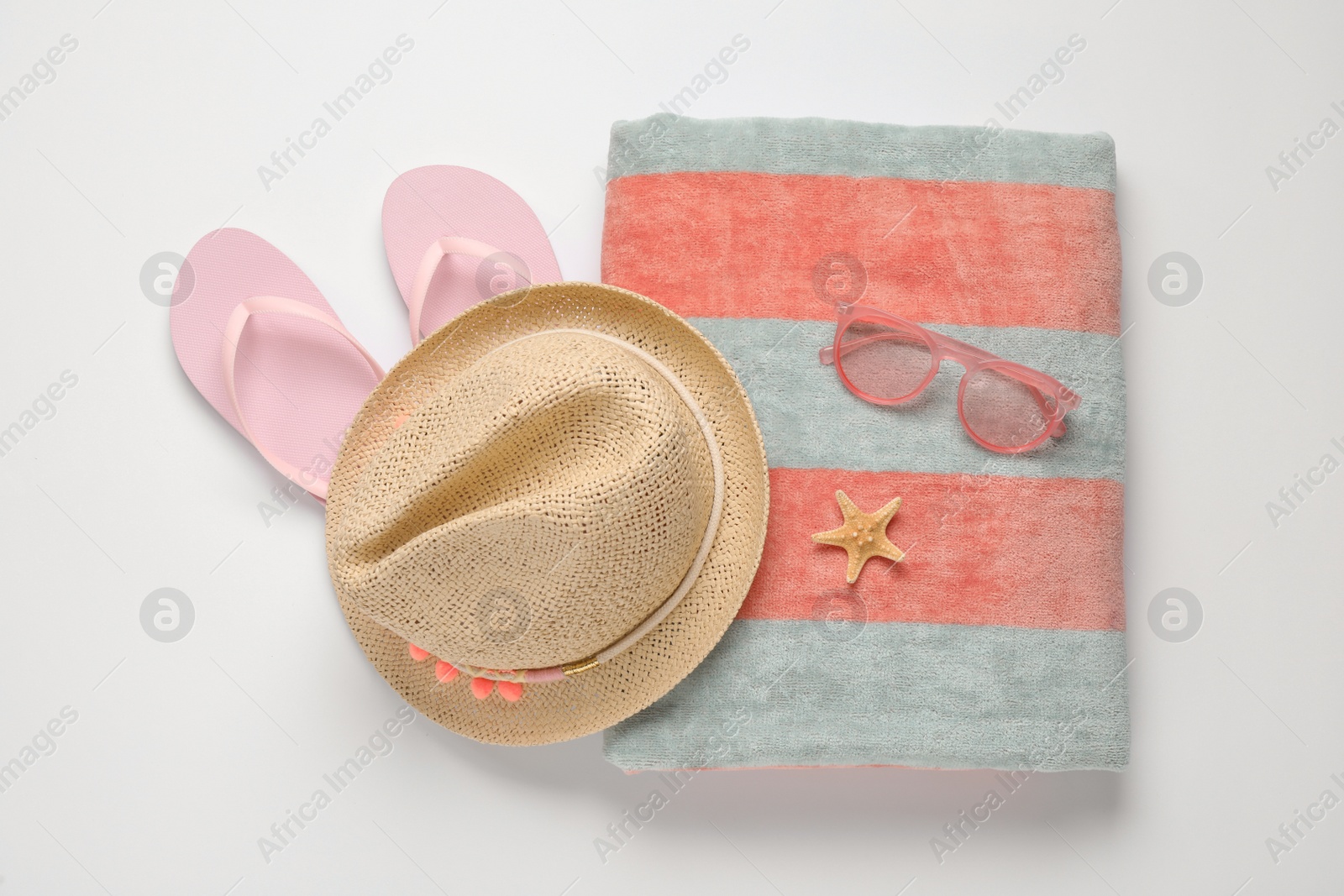 Photo of Beach towel, flip flops, hat and sunglasses on white background, top view