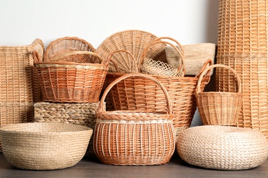 Photo of Many different wicker baskets made of natural material on floor near light wall