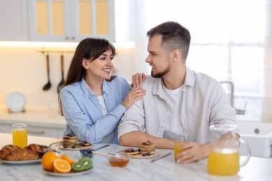 Happy couple having tasty breakfast at home