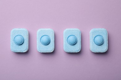 Water softener tablets on violet background, flat lay
